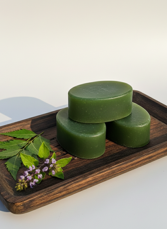 Three green bars of soap on a wooden tray with a leaf and flowers on a white background