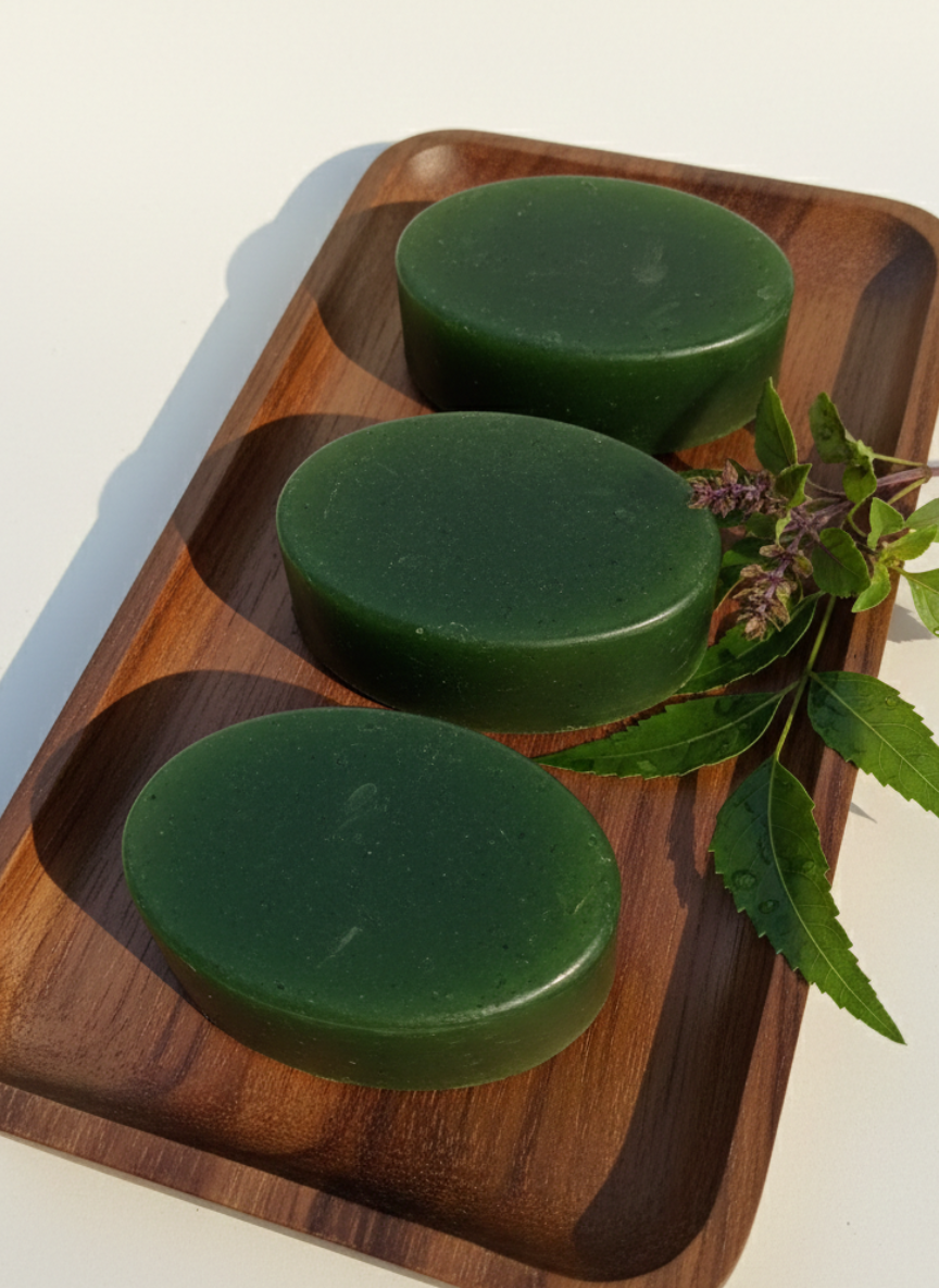 Three green neem tulsi soap  on a wooden tray with lneem tulsi eaves on a light background