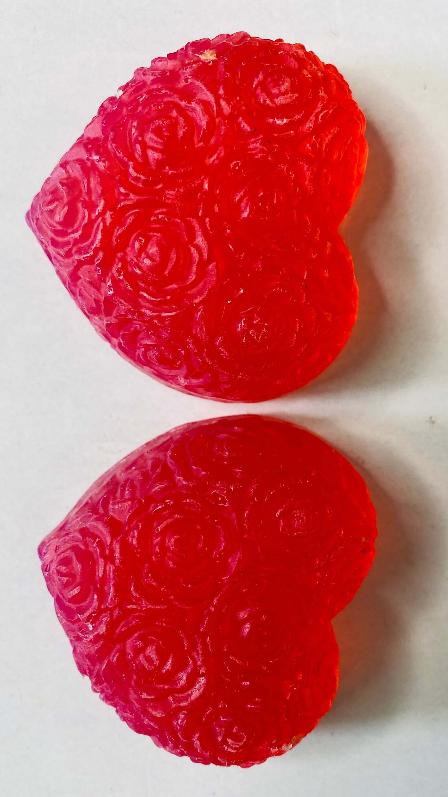 Two red heart-shaped gummy candies  soap on a white background