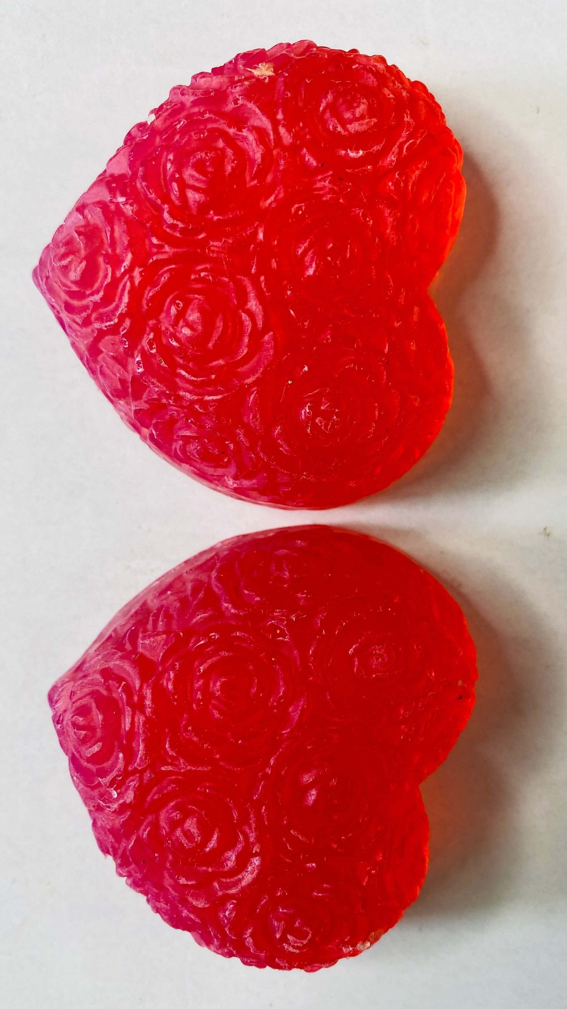 Two red heart-shaped gummy candies  soap on a white background